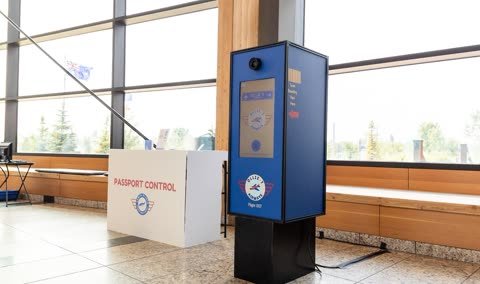 Custom aviation-themed Pick-A-Booth kiosk with an Ollie.7 Airways wrap beside a Passport Control desk.